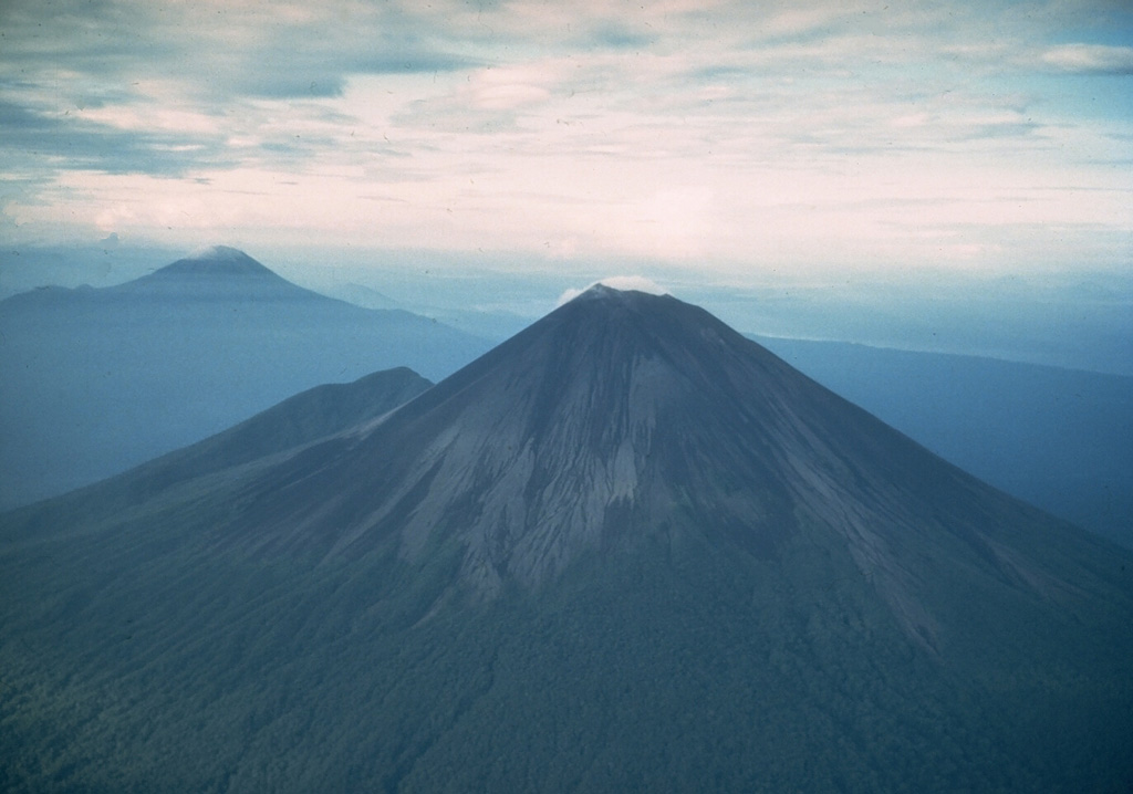 The symmetrical Ulawun is one of Papua New Guinea's most frequently active volcanoes. Ulawun and Bamus volcano (upper left) are the two highest volcanoes of the Bismarck Archipelago, and are known as the Father and South Son volcanoes, respectively. The upper 1,000 m of Ulawun is unvegetated. Historical eruptions date back to the beginning of the 18th century. Photo by Wally Johnson (Australia Bureau of Mineral Resources).