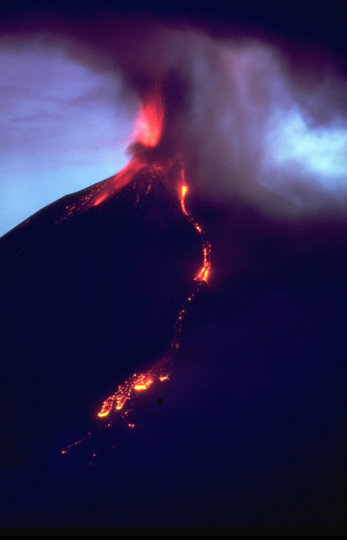 Incandescent lava flows descend the NW flank of Ulawun at dusk on 21 November 1985 as Strombolian activity occurs at the summit. Strombolian explosions began with the onset of the eruption on 17 November. Lava flows began descending the N slope the next day and eventually reached 5.5 km from the summit. On 20 November an ash plume reached an altitude of 7-8 km. The eruption ended the day after this photo was taken. Photo by Wally Johnson, 1985 (Australia Bureau of Mineral Resources).