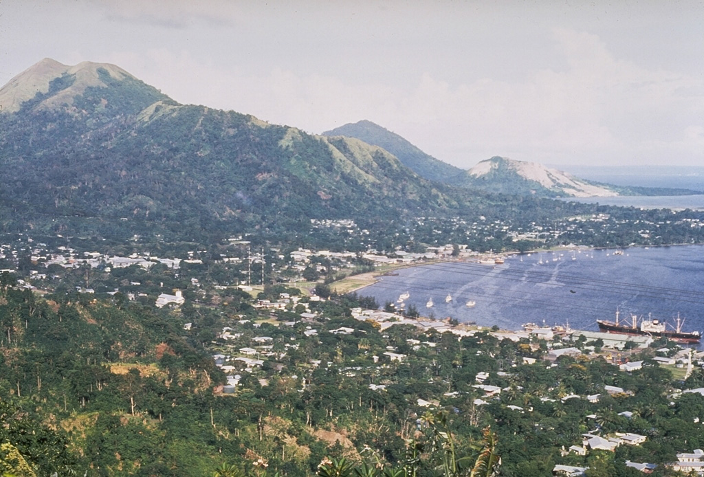 The city of Rabaul is seen here in 1969. The low-lying Rabaul caldera forms a sheltered harbor once utilized by New Britain's largest city. A powerful explosive eruption in 1994 forced its evacuation. The 8 x 14 km caldera opens on the W, where its floor is flooded by Blanche Bay. Two major Holocene caldera-forming eruptions took place as recently as 3,500 and 1,400 years ago. Several post-caldera cones, including Tavurvur to the far right, have recorded eruptions. Photo by Wally Johnson, 1969 (Australia Bureau of Mineral Resources).