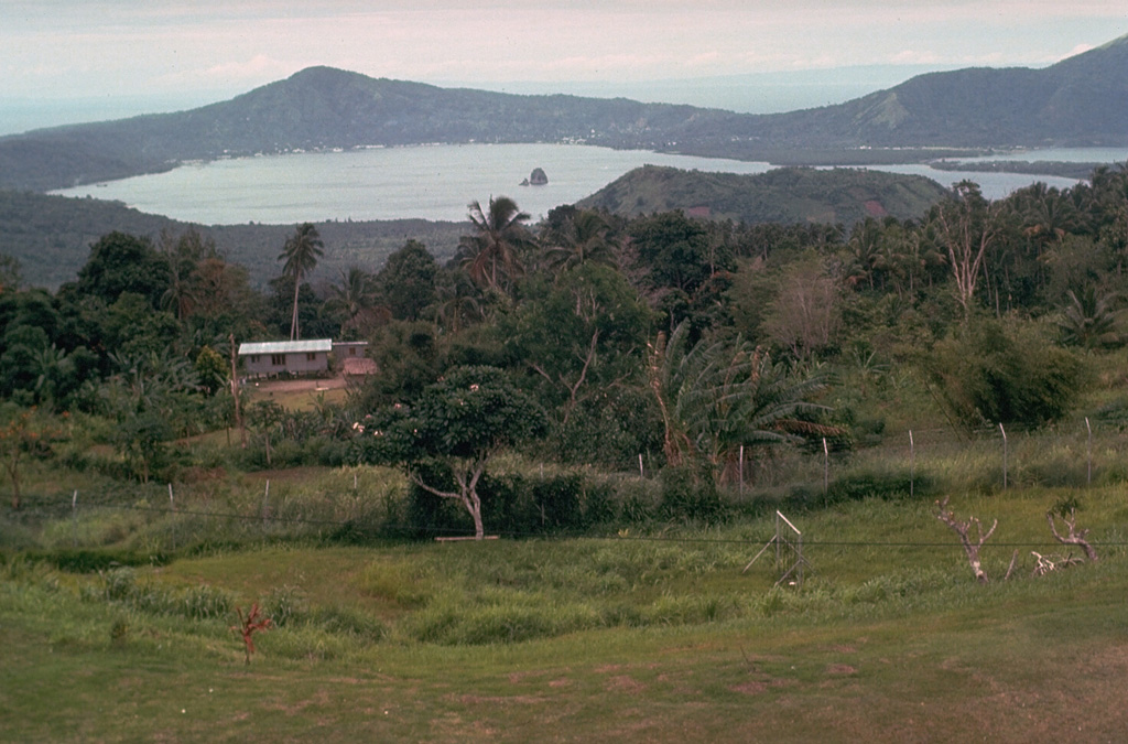 The second of two Holocene caldera-producing eruptions at Rabaul volcano took place about 1,400 years ago. The eruption produced voluminous ashfall and pyroclastic flow deposits, followed by collapse that created the 8 x 14 km caldera, seen here from near its SW rim. The eruption originated from a location near the small, steep-sided island in the center of the bay, Davapia Rocks (also known as The Beehive), an erosional remnant of a post-caldera cone. Photo by Russell Blong, 1980 (Macquarie University).
