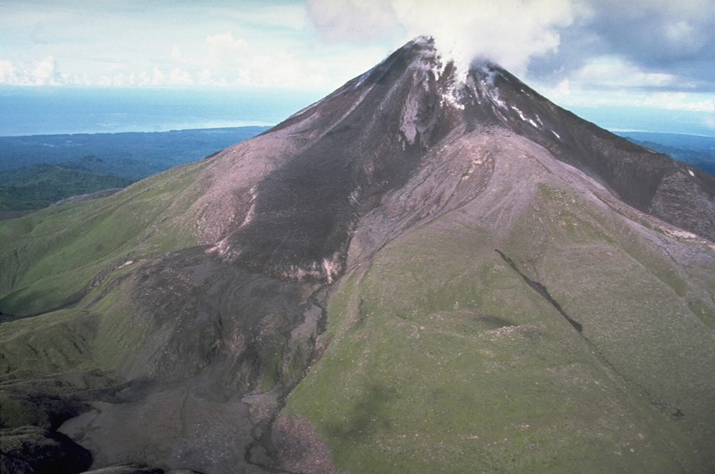 Plumes rise from a slow-moving andesite lava flow descending the NW flank of Bagana on 26 April 1988. The flow at that time had been moving for about 3 or 4 years and is typical of the lava extrusion that began in 1972. This volcano was largely constructed by an accumulation of viscous andesite lava flows like this one.  Photo by Wally Johnson, 1988 (Australia Bureau of Mineral Resources).
