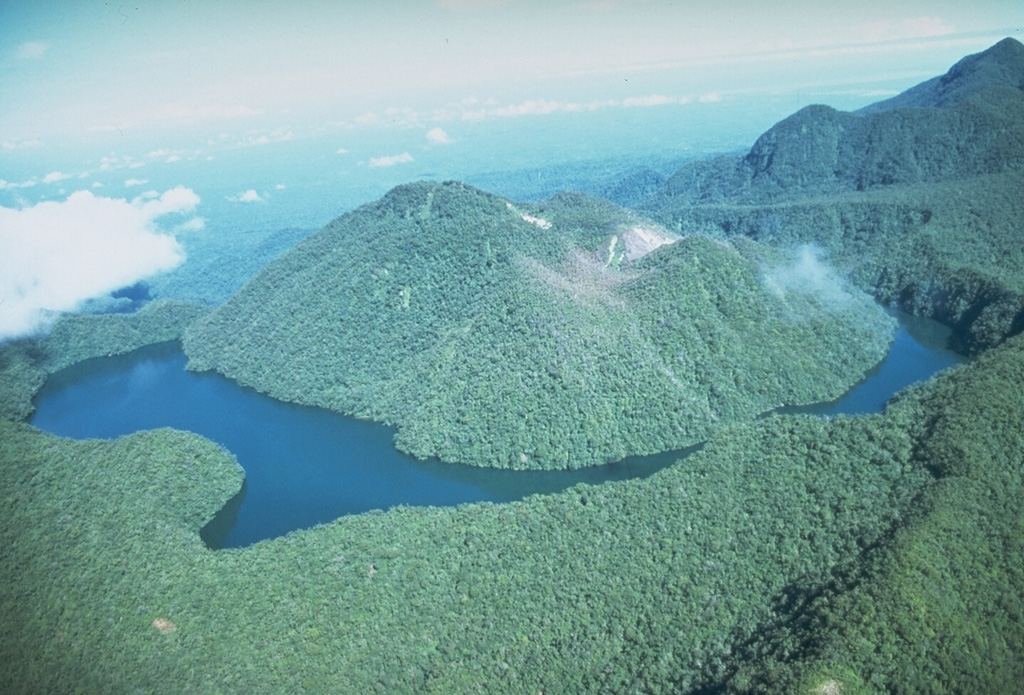 The summit of Loloru on SE Bougainville Island has two nested calderas and forested lava dome within the younger one. Loloru is constructed within the 10 x 15 km Pleistocene Laluai caldera; part of the rim of this outer caldera is seen at the lower right. Pyroclastic flow deposits from the volcano cover much of the southern part of the island. The most recent of several major Holocene explosive eruptions took place about 3,000 years ago. Photo by Wally Johnson, 1988 (Australia Bureau of Mineral Resources).