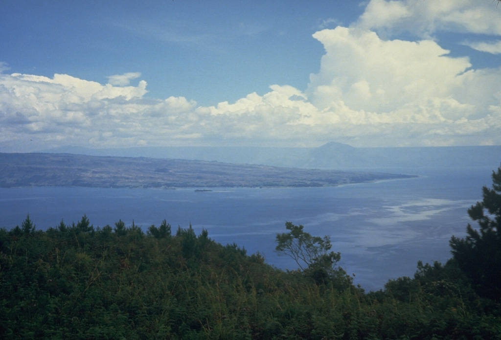 The 35 x 100 km wide Toba caldera, partially filled by Sumatra's Lake Toba, is Earth's largest Quaternary caldera. This view looks W toward the northern end of Samosir Island, which is part of a block that was uplifted after eruption of the Young Toba Tuff (YTT) about 74,000 years ago. The island, once entirely covered by Lake Toba, is formed of caldera-fill deposits of YTT-capped by lake sediments. Photo by Tom Casadevall, 1987 (U.S. Geological Survey)