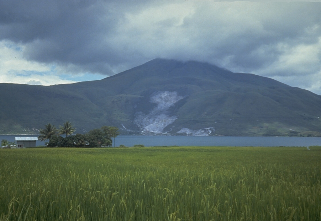 Clouds obscure the summit of Pusukbukit, a young volcano that formed on the western margin of Toba caldera. An active geothermal area forms the light-colored area at the base of the volcano across the strait from Samosir Island on Lake Toba. Photo by Tom Casadevall, 1987 (U.S. Geological Survey)