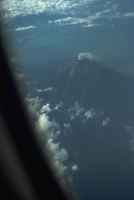 A commercial flight above the Padang Highlands of central Sumatra provides a view of a plume rising from the summit crater of Kerinci, Indonesia's highest volcano. Photo by Tom Casadevall, 1987 (U.S. Geological Survey).