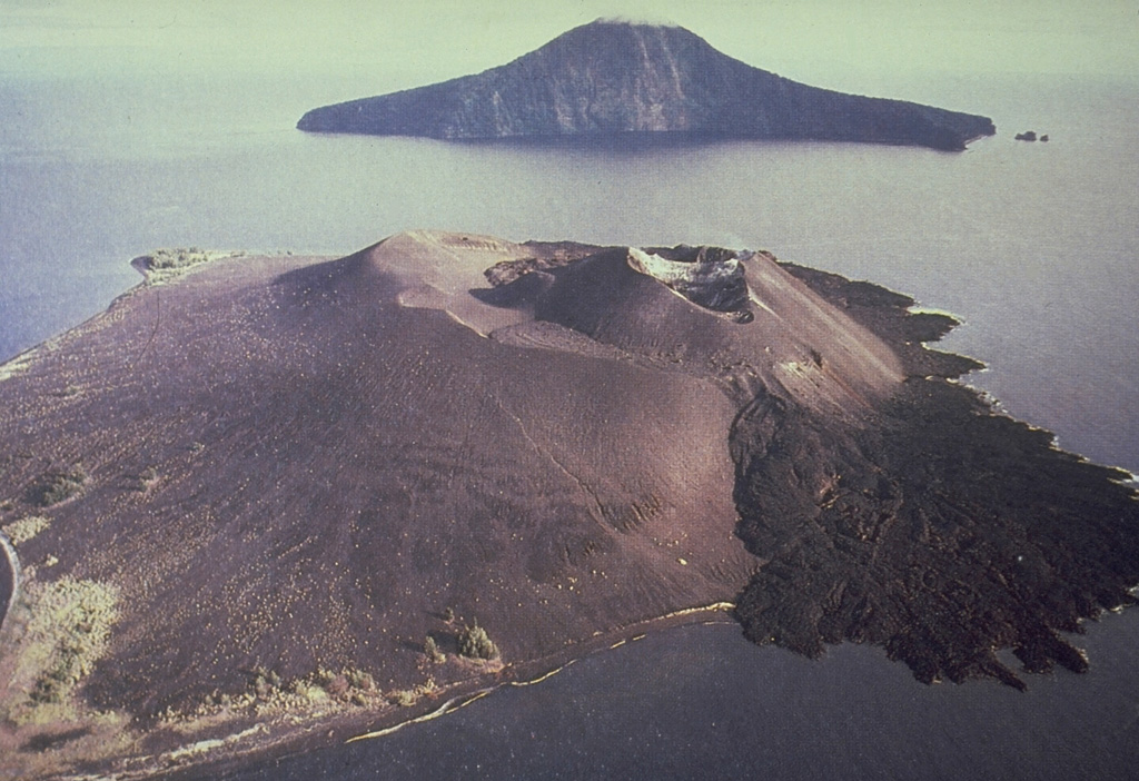 Krakatau volcano lies in the Sunda Strait between Sumatra and Java. The historic eruption of 1883 destroyed much of Krakatau Island, forming a submarine caldera and producing detonations that were heard as far away as Australia, and numerous smaller eruptions have occurred since. Rakata Island in the background is the truncated rim of the 1883 caldera. Anak Krakatau in the foreground is a post-caldera cone that first breached the surface of the sea in 1928 and has been in frequent activity since then. The black lava flow at the right side of the photo was erupted in 1975. Photo courtesy Volcanological Survey of Indonesia, 1979.