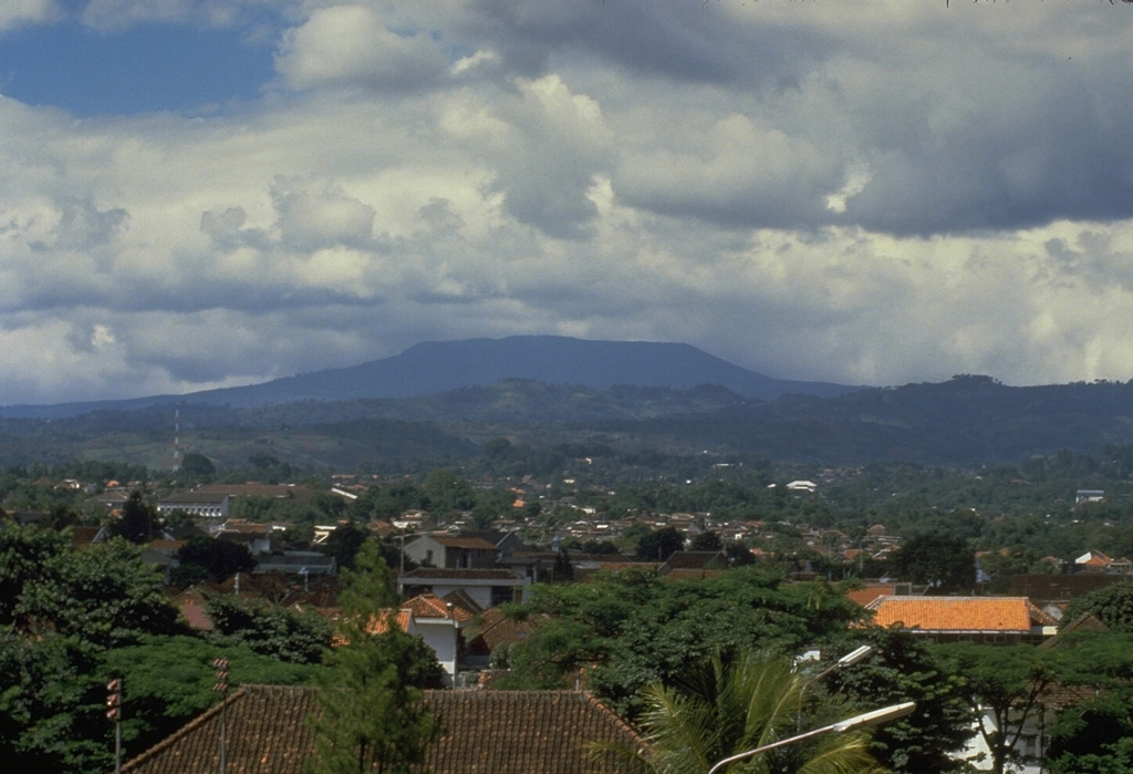 The broad Tangkuban Parahu, known locally as the mountain of the "upturned boat," dominates the skyline immediately N of Indonesia's former capital city of Bandung. The volcano is truncated by the 6 x 8 km Pleistocene Sunda caldera. A series of nine overlapping craters form a 1 x 1.5 km wide elliptical depression at the summit of the post-caldera cone. Minor phreatic eruptions have occurred in historical time. Photo by Tom Casadevall, 1987 (U.S. Geological Survey).