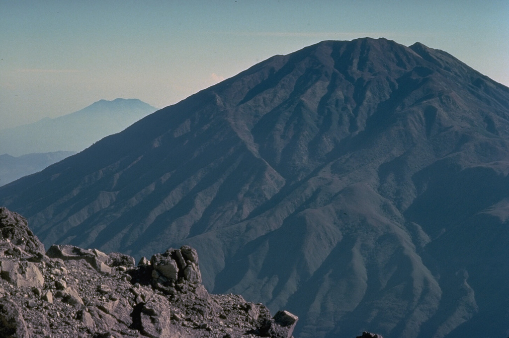 The ribbed surface of Gunung Merbabu towers to the north of Merapi volcano.  The most recent magmatic eruptions from Merbabu originated from a NNW-SSE fissure system that cuts across the summit and fed large-volume lava flows on the northern and southern flanks.  Moderate explosive eruptions have occurred from Merbabu's summit crater in historical time.   Copyrighted photo by Katia and Maurice Krafft, 1976.