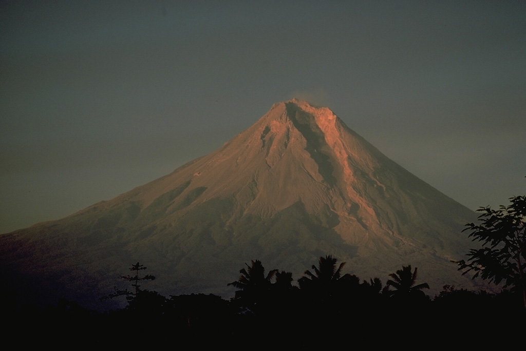 Merapi, one of Indonesia's most active volcanoes, towers above the major regional cultural and religious center of Yogyakarta in central Java.  The prominent SW side breach seen here funnels rockfalls, pyroclastic flows, and mudflows associated with long-term growth of summit lava domes onto populated agricultural lands beneath the volcano.  Merapi eruptions have frequently produced major devastation during historical time. Copyrighted photo by Katia and Maurice Krafft, 1976.