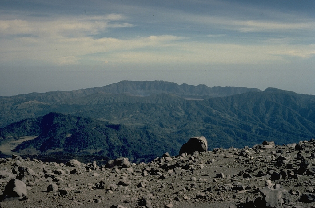 The Tengger caldera complex forms the large depression in the background of this view from Semeru volcano to its south.  The compound caldera consists of the 16-km-wide Ngadisari caldera and the younger Sandsea caldera.  A faint steam plume lingers at the center of the photo above Bromo, the source of all historical eruptions at Tengger caldera.  Gunung Bromo is part of a complex of pyroclastic cones constructed within the Sandsea caldera. Copyrighted photo by Katia and Maurice Krafft, 1971.