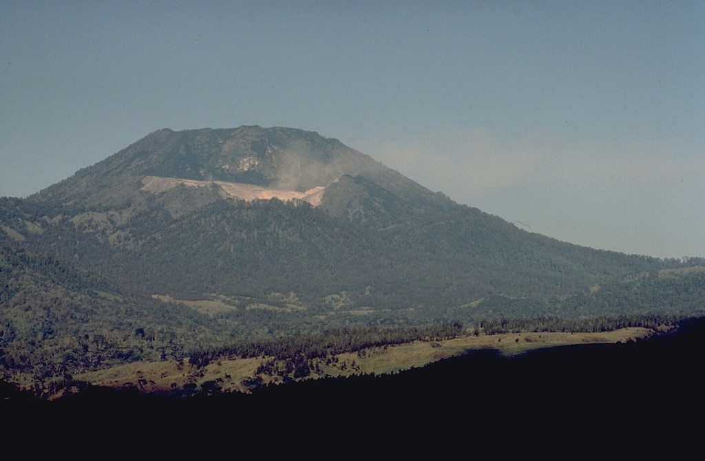 The light-colored area below the summit of flat-topped Gunung Merapi, the highest peak of Ijen volcano, is the crater rim of Kawah Ijen, the renowned sulfur-bearing lake.  Gunung Merapi, seen here from within the caldera, was constructed over the eastern rim of the 20-km-wide Ijen caldera. Copyrighted photo by Katia and Maurice Krafft, 1971.