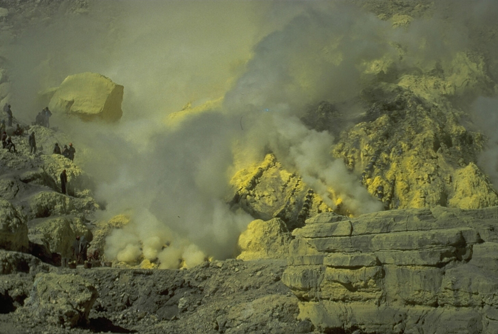 Sulfur miners (left) extract sulfur from the crater walls of Kawah Ijen. Large baskets of sulfur are carried up to the crater rim and down its flanks. The sulfur factory is located at Jambu, on the SE flank above Banyuwangi. Photo by Tom Casadevall, 1987 (U.S. Geological Survey).