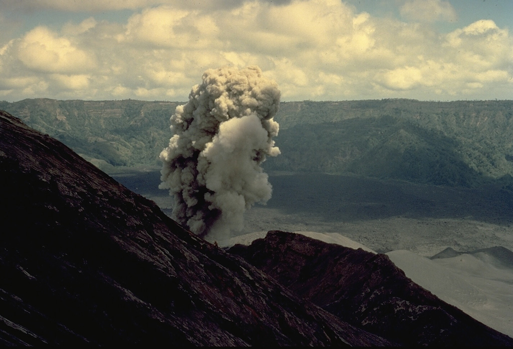 A small ash-bearing eruption column rises from a vent just below the summit of Batur volcano on Bali on August 11, 1971.  Batur's outer caldera wall forms the ridge in the background.  The maximum height of the ash column during the minor 1971 eruption was 300 m. Copyrighted photo by Katia and Maurice Krafft, 1971.