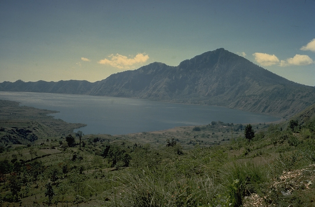 Gunung Abang forms the 2152-m high point along the eastern wall of Batur's outer caldera.  The boundary of an inner caldera, within which Batur volcano (out of view to the left) was constructed, is obscured on its SE side beneath the surface of  the caldera lake.  Lava flows from Batur volcano extent into the lake at the left. Copyrighted photo by Katia and Maurice Krafft, 1971.