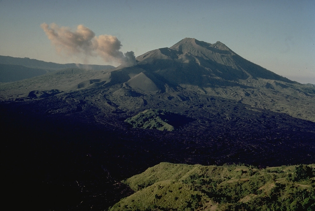 The small 1717-m stratovolcano Batur on the island of Bali was constructed within the inner of two nested calderas.  The outer 10 x 13 km caldera contains a crater lake; the inner 7.5-km-wide caldera was formed about 23,670 years ago. Historical eruptions have produced minor explosive activity and lava flows primarily from vents along a NE-SW-trending line.  Several historical lava flows have reached the southern caldera wall in the foreground. Copyrighted photo by Katia and Maurice Krafft, 1971.