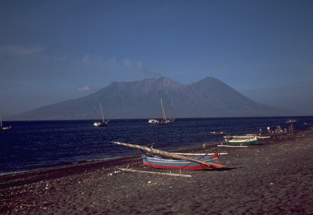 Sangeang Api is a small volcanic island off the NE coast of Sumbawa Island. Two large cones, Doro Api in the center and Doro Mantai on the right, were constructed within and on the south rim of a largely obscured caldera. Intermittent eruptions have been recorded since 1512 and it has been frequently active in the 20th century. Photo by Tom Casadevall, 1985 (U.S. Geological Survey).