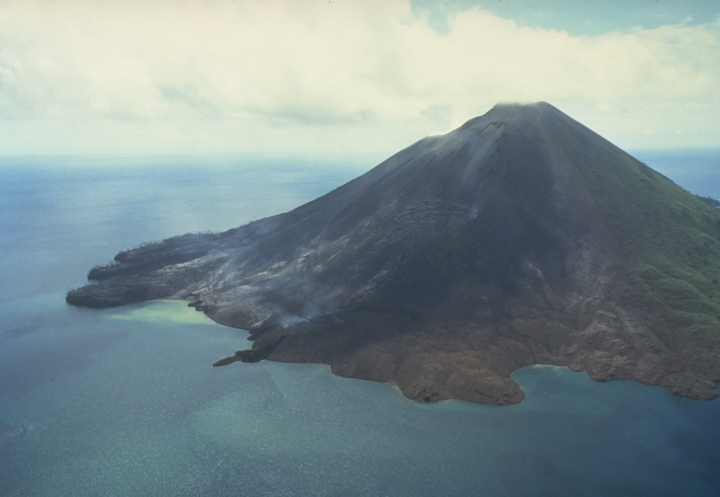 Gunung Api volcano is seen here in an aerial view from the south on May 19, 1988.  The narrow peninsula at the left-center is the terminous of a still-steaming lava flow that was erupted from a vent low on the SW flank beginning on May 9.  Another flow erupted from a vent at about 150 m elevation on the SW flank also reached the sea immediately to the west.  The May 9 vents were located along an arcuate N-SSW-trending fissure that cut across the summit of the volcano. Photo by Tom Casadevall, 1988 (U.S. Geological Survey).