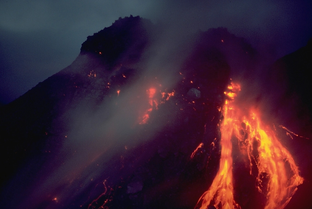 A nighttime view shows incandescent rockfall on February 21, 1988, associated with growth of Anak Ranakah lava dome on Indonesia's Flores Island.  The new lava dome began forming on December 28, 1987, and reached a height of 150 m by June 1988. Copyrighted photo by Katia and Maurice Krafft, 1988.