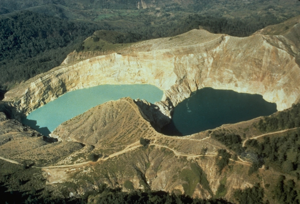 The two crater lakes of Kelimutu volcano on Indonesia's Flores Island are seen in this aerial view from the SW. Tiwu Nua Muri Kooh Tai (Lake of Young Men and Maidens) on the left and Tiwu Ata Polo (Bewitched or Enchanted Lake) are separated by a narrow crater wall about 35 m high. Phreatic eruptions have occurred from Tiwu Nua Muri Kooh Tai in the 19th and 20th centuries. Photo by Tom Casadevall, 1986 (U.S. Geological Survey).