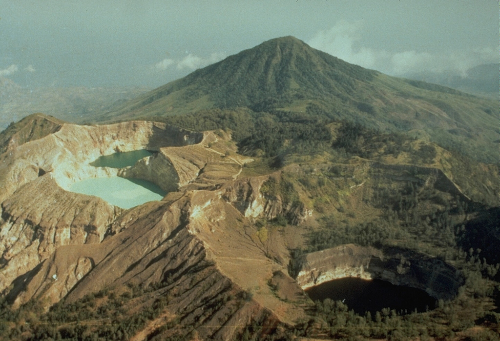 The summit of Kelimutu volcano is elongated 2 km in a NNW-ESE direction, and contains three crater lakes of different colors that are one of the most popular tourist destinations on Flores Island.  This view from the north shows the three crater lakes with Keli Bara cone in the background.  Phreatic explosions have occurred from the middle lake in historical time. Copyrighted photo by Katia and Maurice Krafft, 1971.