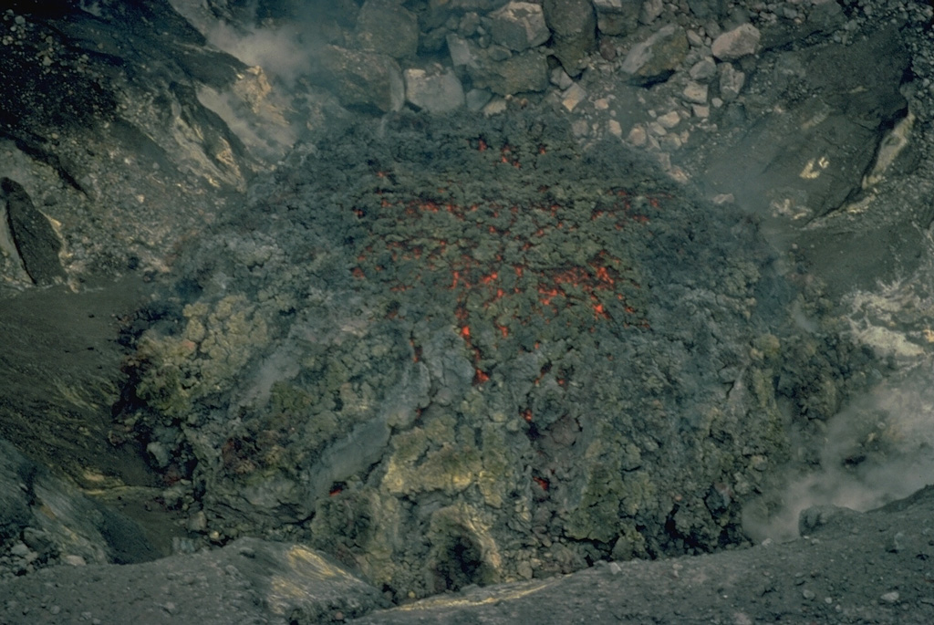 Incandescence is visible in cracks in the surface of a small lava dome in Tompuluan crater of Lokon-Empung volcano in June 1976.  This was the second of two small lava domes emplaced during an eruption that began in November 1975, and lasted, with intermittent ash eruptions, until 1980. Copyrighted photo by Katia and Maurice Krafft, 1976.