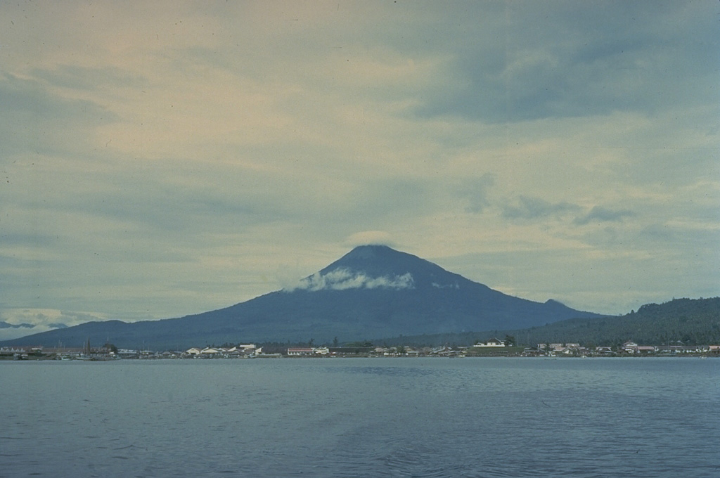 A small cloud caps the summit of symmetrical Klabat volcano, located on the northern arm of Sulawesi Island.  Gunung Klabat contains a summit crater, elongated in a NW-SE direction, that is occupied by a shallow crater lake.  No eruptions of Klabat are known in historical time. Copyrighted photo by Katia and Maurice Krafft, 1971.