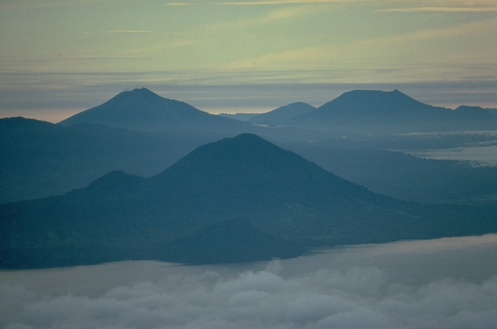 This view from the summit of Ternate Island shows the Halmahera Island volcanoes of Jailolo in the foreground, Gamkonora on the left, and flat-topped Ibu volcano on the right.  Jailolo volcano has no known historical eruptions, but youthful lava flows are located on the eastern flank.  Gamkonora is one of Halmahera's most active volcanoes, while Ibu, with its nested summit craters, one of which has a crater lake, has erupted only once in historical time, in 1911. Copyrighted photo by Katia and Maurice Krafft, 1976.