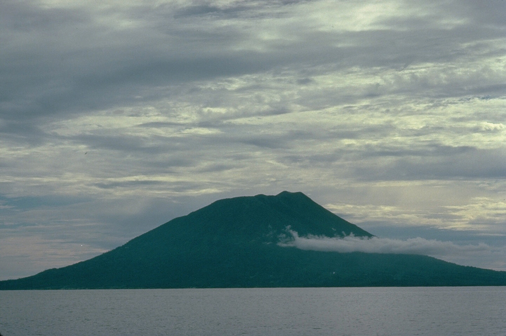 Makian volcano, one of a chain of islands off the western coast of Halmahera Island, has been the source of infrequent, but violent eruptions that have devastated villages on the 10-km-wide island.  The 1357-m summit is truncated by a 1.5-km-wide crater containing a small crater lake on the NE side.  Two large valleys, on the east and north sides, drain to the coast.  Four flank cones occur on the west side. Copyrighted photo by Katia and Maurice Krafft, 1976.
