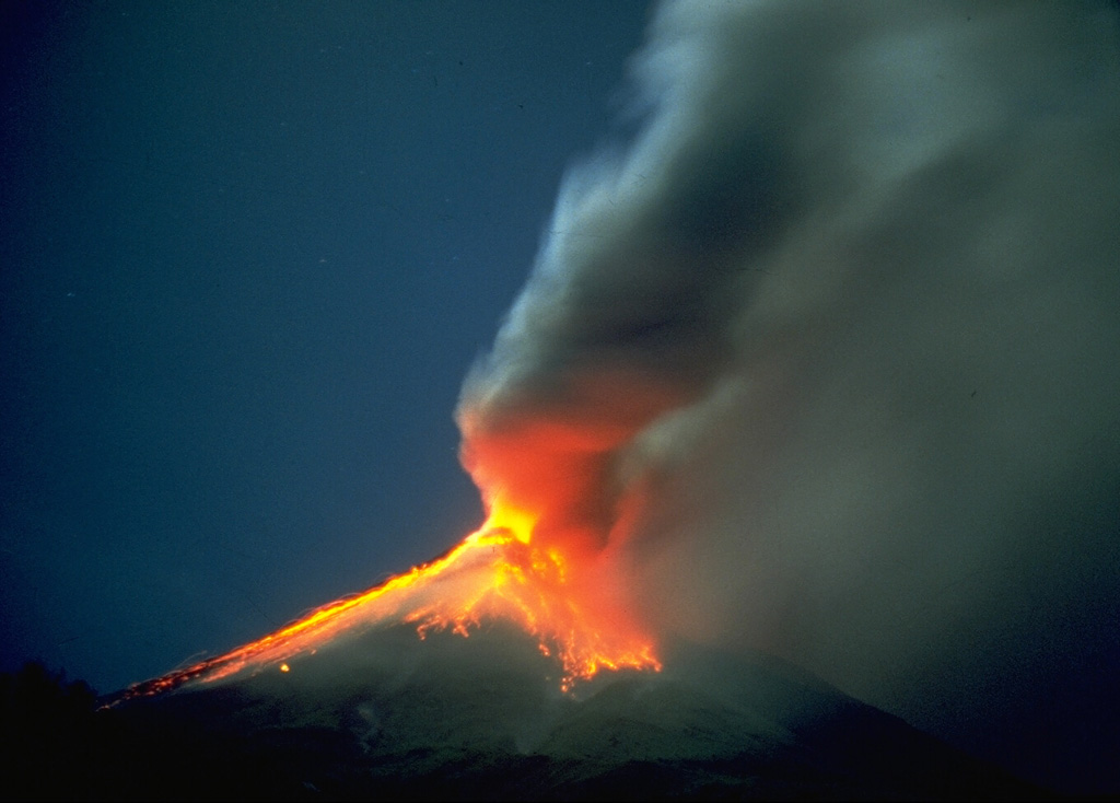 This time-lapse photo taken on 12 September 1984 shows incandescent blocks that were ejected by explosive eruptions and are cascading down the flanks of Mayon. The incandescence is reflected in the base of the ash plume to the right.  Photo by Rene Arcante, 1984 (courtesy Philippine Institute of Volcanology and Seismology).