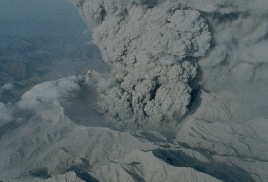 An ash plume rises from the new caldera of Pinatubo volcano on 22 June 1991. The 2.5-km-wide caldera, seen here from the N, was formed by collapse of the summit following a Plinian eruption on 15 June. Ash plumes continued for about a month before becoming intermittent prior to the end of the eruption on 2 September. Light-colored ash deposits cover the flanks of the formerly forest-covered volcano. Photo by R. Batalon, 1991 (U.S. Air Force).