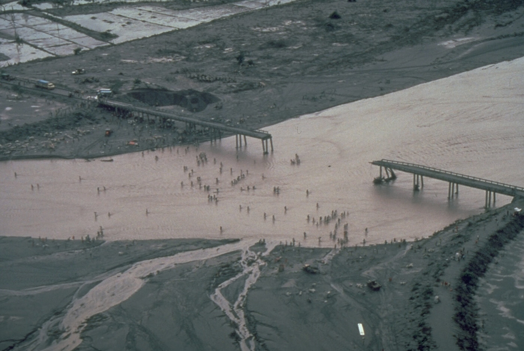 Residents in this July 1991 photo had to cross the shallow Santo Tomás River, SW of Pinatubo, on foot after lahars (volcanic mudflows) destroyed the bridge between the villages of San Rafael and Santa Fe. Devastating lahars affected broad lowland areas on all sides of Pinatubo in the years following the 1991 eruption. Photo by Chris Newhall, 1991 (U.S. Geological Survey).