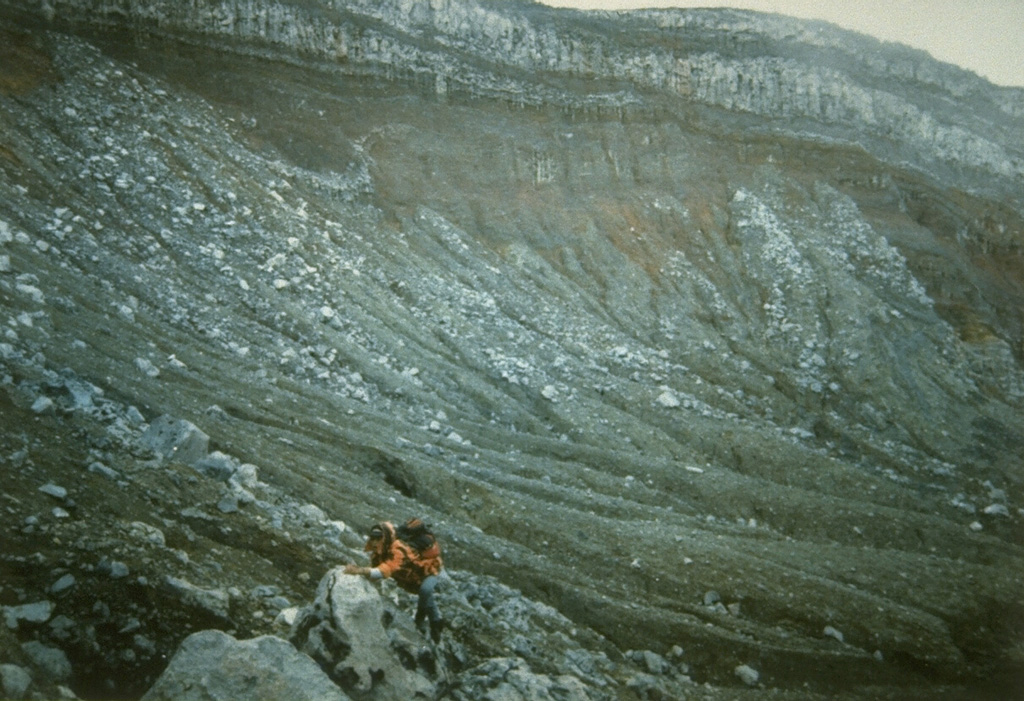 A scientist from the Volcanological Survey of Indonesia investigates rocks in the summit crater of Dempo volcano. The Kawah Merapi crater exposes bedded pyroclastic material that is overlain by a series of light-colored lava flows. Photo by R. Whandyo, 1992 (Volcanological Survey of Indonesia).