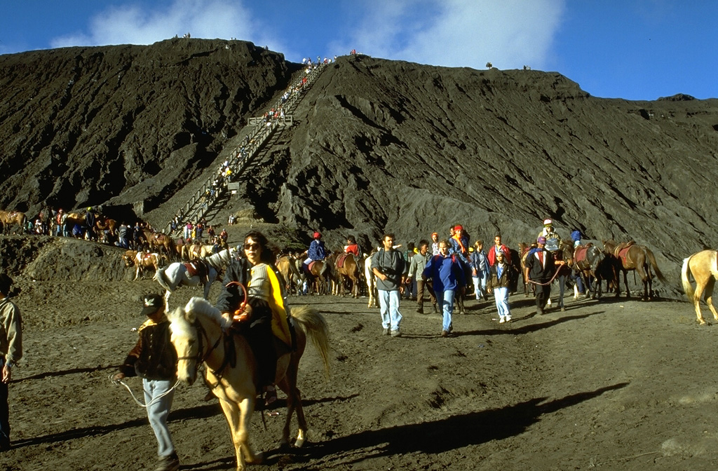 Bromo, a historically active cone within the Tengger caldera, is one of Indonesia's most visited volcanoes. Legends portray the formation of Bromo, whose name means "fire." Visitors climb a broad stairway to the crater rim after reaching the foot of the cone from the rim of Tengger caldera by foot or horseback across the flat-bottomed Sandsea caldera. Photo by Lee Siebert, 1995 (Smithsonian Institution).