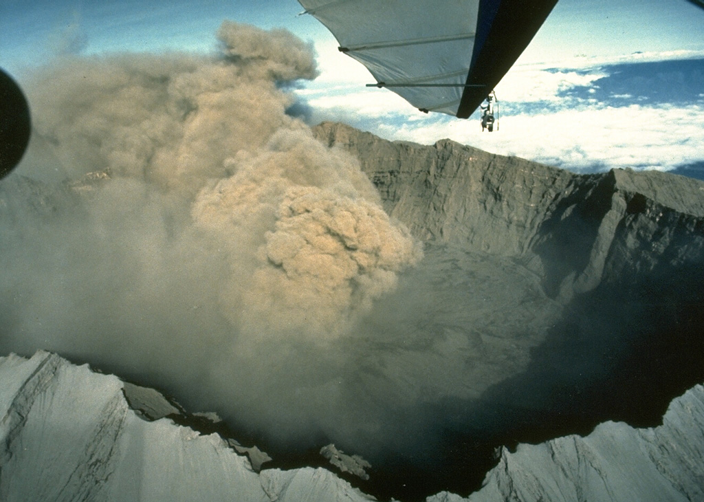 An ash plume from the scoria cone within the caldera rises above the rim of the 2-km-wide Raung caldera in July 1988. Raung has erupted frequently in historical time. Photo by Willem Rohi, 1988 (Volcanological Survey of Indonesia).
