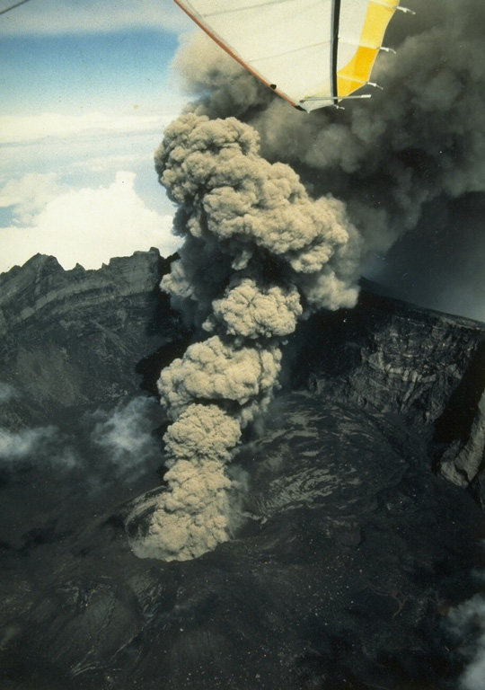 An eruption plume from a scoria cone on the floor of the 2-km-wide Raung caldera rises high above the caldera rim in July 1988. Frequent explosive eruptions occurred at Raung from 1987 through July 1989. During August and September 1988 more than 300-400 individual eruptions were recorded. Photo by Willem Rohi, 1988 (Volcanological Survey of Indonesia).