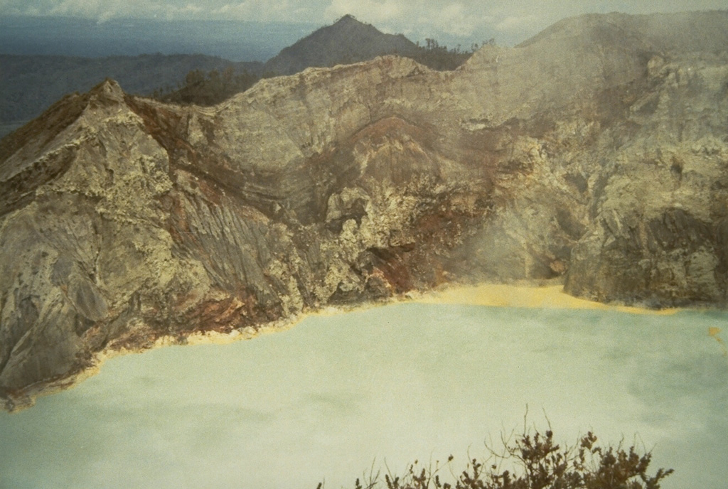 Hydrothermally altered rocks are exposed in the NW crater wall of Kawah Ijen in 1973. Rafts of yellow floating sulfur line the shore of the turquoise-colored crater lake. The walls of the 1.2-km-wide crater rise to more than 200 m above the surface of the lake, which has a maximum depth of 200 m. Photo by Sumarma Hamidi, 1973 (Volcanological Survey of Indonesia).