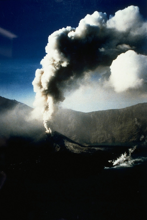 An ash plume rises on 30 June 1994 above Barujari, a cone on the floor of Rinjani's Segara Anak caldera. A small plume is visible to the lower right from a lava flow that began erupting during the earlier stages of the eruption. Photo courtesy of Volcanological Survey of Indonesia, 1994.