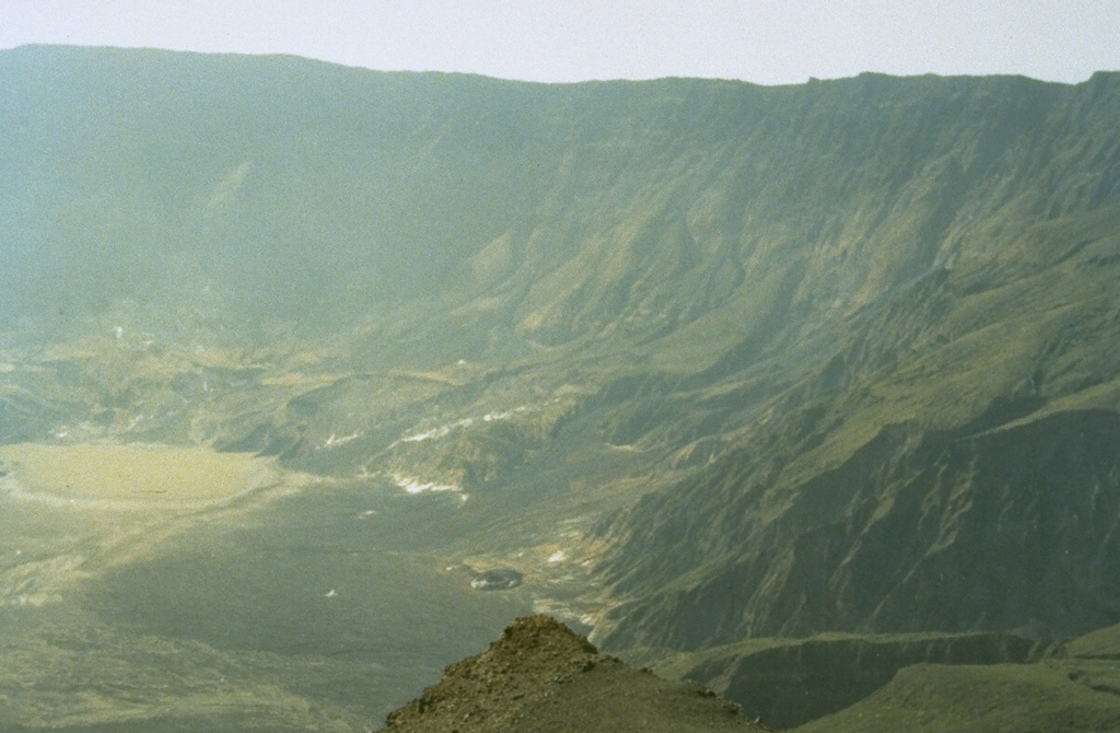 Tambora's caldera, seen here from the western rim, was formed during the eruption of 1815 following the ejection of about 30-50 km3 DRE (dense rock equivalent) of ashfall and pyroclastic flows. This was history's largest explosive eruption and followed low-level eruptive activity that began in 1812. Only a few minor eruptions have taken place since formation of the 6-km-wide and 1,250-m-deep caldera. The last eruption produced a lava flow on the caldera floor and is known only to have occurred sometime between 1947 and 1968. Photo by Rizal Dasoeki, 1986 (Volcanological Survey of Indonesia).