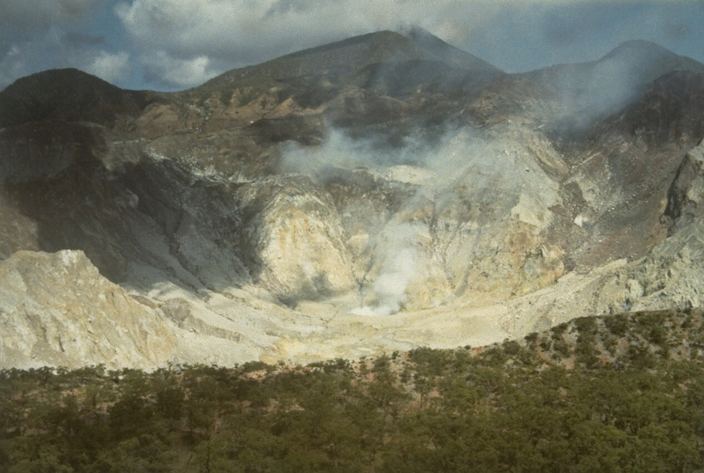 The steaming summit caldera of Gunung Sirung volcano is seen here from the eastern caldera rim.  Sirung volcano lies at the NE end of a 14-km-long line of volcanic centers forming a peninsula at the southern end of Pantar Island.  A lava dome (center) at the western side of the caldera forms the summit of Gunung Sirung volcano; other cones along the chain to the SE increase in height.  The 2-km-wide summit caldera has been the source of small phreatic eruptions during the 20th century. Photo by L.D. Reksowirogo, 1972 (Volcanological Survey of Indonesia).