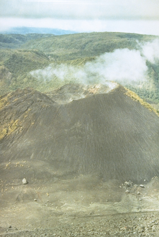 The broad 1549-m-high Sempu stratovolcano (background) is seen here from the summit of neighboring Soputan volcano.  The prominent cone in the center is Aeseput, a 20th-century cone constructed on the NW flank of Soputan.  Gunung Sempu volcano was constructed within a 3-km-wide caldera.  Kawah Masem maar was formed in the SW part of the caldera and contains a crater lake and fumarolic areas that have been the site of sulfur extraction.  No historical eruptions are known from Sempu.  Photo by Ruska Hadian, 1973 (Volcanological Survey of Indonesia).