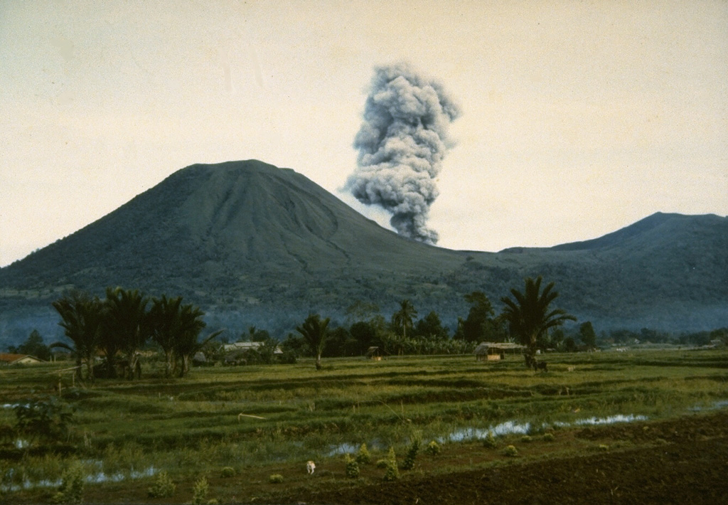 An eruption plume, viewed from the east, rises from Tompaluan crater in the saddle between Lokon (left) and Empung (right) volcanoes on July 15, 1986.  Intermittent explosive eruptions took place from March 22, 1986, until May 13, 1987 from Lokon-Empung, one of the most active volcanoes of Sulawesi Island. Photo by Ruska Hadian, 1986 (Volcanological Survey of Indonesia).