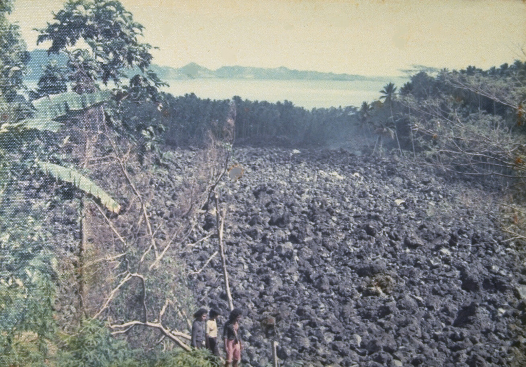 A blocky lava flow, seen here from the NW, descends the southern flank of Karengetang (Api Siau) volcano in 1976.  An eruption began on September 15 from a new vent on the south flank at 1000 m altitude.  The lava flow traveled 7 km to reach the sea on the SW flank.  Pyroclastic flows from collapse of the lava flow's terminous scorched vegetation near the flow, destroyed houses, and caused one fatality.  Minor cauliflower-like gas emission accompanied by rumblings continued until the end of the eruption in September of the following year. Photo by J. Matahelumual, 1976 (Volcanological Survey of Indonesia).
