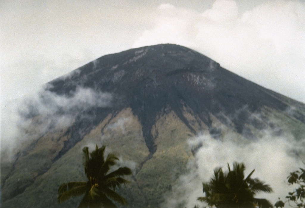 Gamalama volcano (also known as the Peak of Ternate), one of the most active volcanoes of Indonesia, forms Ternate Island off the western coast of Halmahera.  The northern and youngest of three cones forming the summit of Gamalama is seen here from the NE.  Unvegetated areas in this 1994 photo consist of the ejecta blanket from recent explosive eruptions.  Frequent eruptions have occurred since the 16th century, most of which originated from the summit vent. Photo by Gatot Sugiharto, 1994 (Volcanological Survey of Indonesia).
