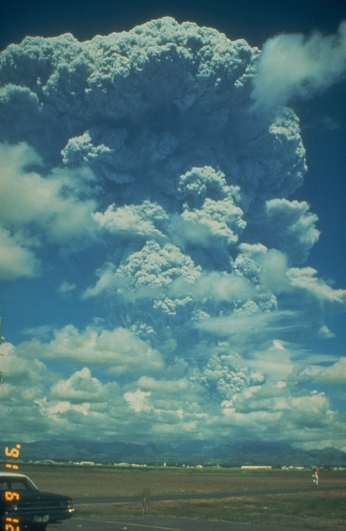 A large Plinian ash plume from Pinatubo towers above Clark Air Base on 12 June 1991. The eruption column reached an altitude of 19 km. This was the first in a series of powerful eruptions that reached a climax on 15 June. The eruption that day produced a series of large pyroclastic flows that covered all sides of the volcano and resulted in collapse of the summit, creating a 2.5-km-wide caldera. Photo by Dave Harlow, 1991 (U.S. Geological Survey).