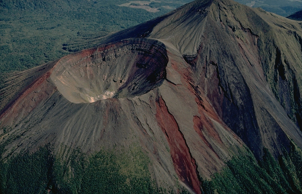 The Takachiho composite volcano, at the SE end of the Kirishima volcano group, consists of four overlapping edifices that are aligned in an E-W direction.  The first eruptions built stratovolcanoes at the east and west ends of the complex.  Thirdly, the Takachiho-no-mine volcano (upper right) was constructed.  The last stage of activity produced Ohachi volcano at the western end (left).  Its 500-m-wide crater has been the most active of the Kirishima volcano group during historical time. Copyrighted photo by Katia and Maurice Krafft.