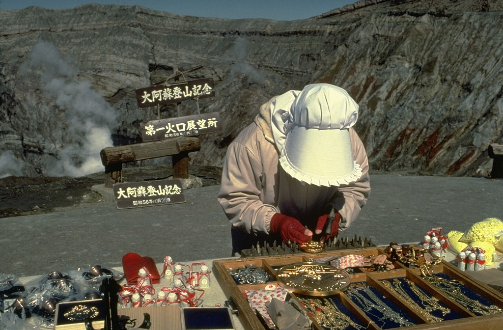 A souvenir vendor sells her wares on the crater rim of Naka-dake, the active cone of Aso caldera.  The caldera is readily accessible by toll road and cable car and is one of Kyushu's most popular tourist destinations.  Frequent eruptions prompt closure of the crater to tourists. Copyrighted photo by Katia and Maurice Krafft, 1981.