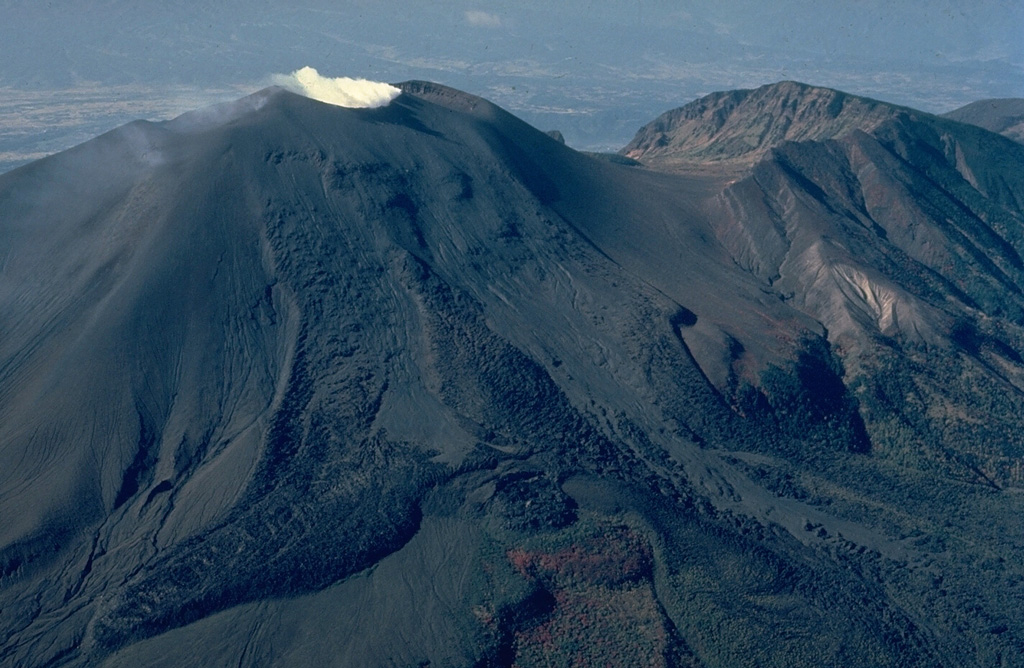 Asama, Honshu's most active volcano, has an historical record dating back more than 1300 years.  The modern cone of Maekake-yama, shown steaming here at the left, is situated east of the horseshoe-shaped remnant of an older andesitic volcano, Kurofu-yama (right), that was destroyed by a late-Pleistocene landslide about 20,000 years ago.  Maekake-yama is probably only a few thousand years old, but has had several major plinian eruptions, the last two of which occurred in 1108 and 1783 CE.    Copyrighted photo by Katia and Maurice Krafft, 1981.