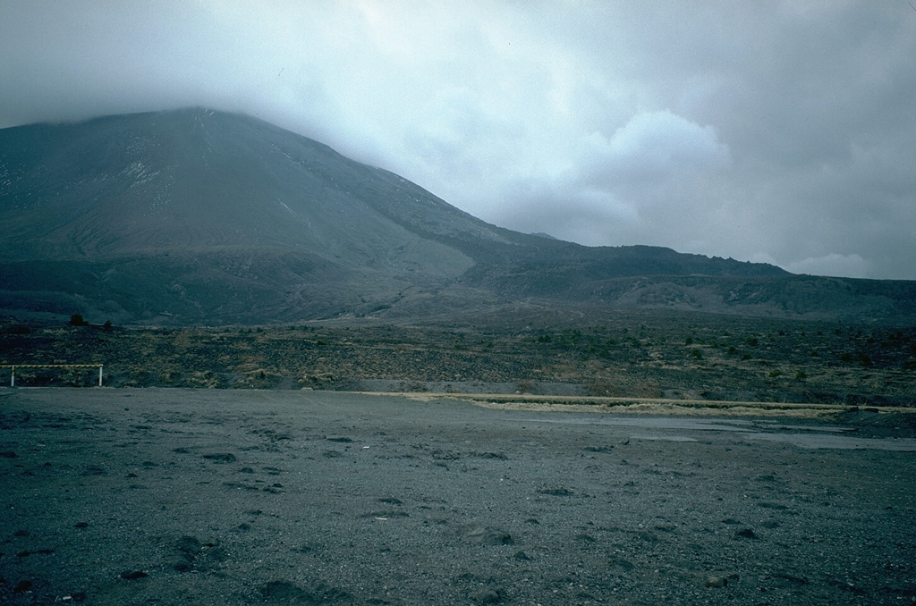This view of Asamayama from the NE shows deposits of one of the largest historical eruptions of the volcano. The flat surface in the foreground is a pyroclastic flow deposit from the 1783 eruption. Behind it is the 1783 Onioshidashi lava flow that descended the north flank near the right horizon. The 1783 eruption began on 9 May and devastating pyroclastic flows and lahars on 4 and 5 August caused many fatalities. The lava flow was emplaced at the end the eruption, which ceased on 5 August. Photo by Tom Simkin, 1993 (Smithsonian Institution).