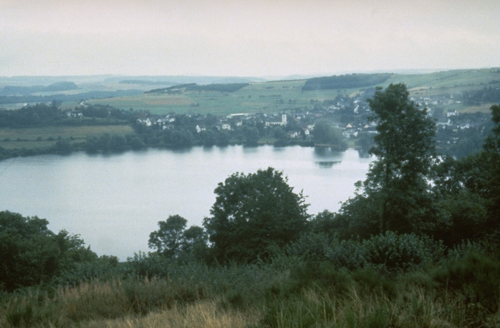 The Mehrener maar is one of about 80 maars of the West Eifel Volcanic Field. The village of Mehrener is located on the shore of a lake partially filling the crater, whose rim lies behind the village. Maars, scoria cones, and small stratovolcanoes cover an area of 600 km2, W of the Rhine River. Most of the volcanic features formed during eruptions between about 730,000 and 10,000 years ago. Photo by Richard Waitt, 1990 (U.S. Geological Survey).