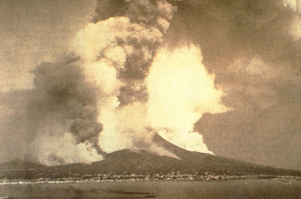 This photograph of Vesuvius looking east across the Bay of Naples depicts the major eruption of April 1872. A vigorous eruption plume rises from the summit crater and ash plumes also rise from a NW flank fissure that fed a lava flow that traveled far down the W flank, overrunning several villages. Steam also rises above another lava flow below and to the right of the summit. This eruption began with lava effusion in December 1870. Photo courtesty of Roberto Scandone (University of Rome).